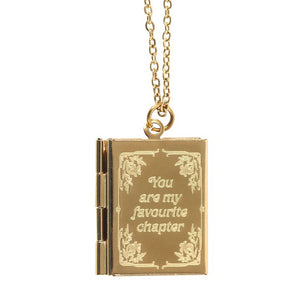 Close-up of the gold-toned locket pendant with engraved floral border and sentimental phrase.