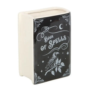 Reverse angle of ceramic spellbook vase, showing cream-coloured ceramic back with book-like ridges and black illustrated cover.