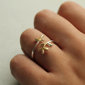 Close-up of the ring on a hand, showcasing its delicate botanical design.