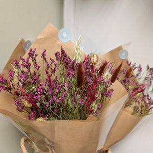 Two stunning Burgundy Dried Flower Arrangements wrapped in kraft paper, displayed against a neutral wall.