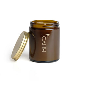 Open amber jar candle with gold lid beside it – CAHM Clove, Orange & Cedarleaf soy candle.