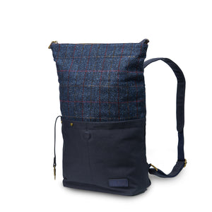 Angled: Navy Over Check Tartan Canvas Backpack with Harris Tweed® (angled view) with adjustable straps. Showcasing the large size of the backpack.