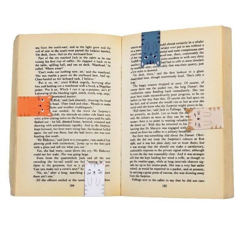 Four cat bookmarks in use marking pages of an open vintage book