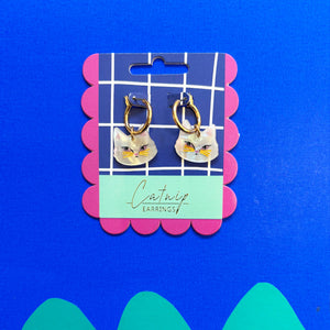 Packaged Catnip Cat Hoop Earrings on a blue background – The earrings displayed in their original packaging with a whimsical cat design, set against a blue background with scalloped edges.