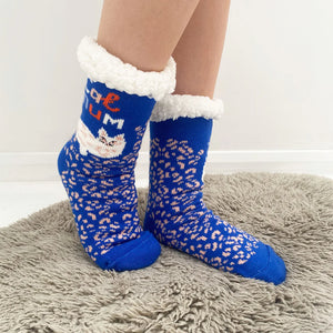 Side view of Catnip Cozy Slipper Socks worn on feet, highlighting the plush white cuff, blue and pink patterned knit, and cute cat illustration with “Cat Mum” text.