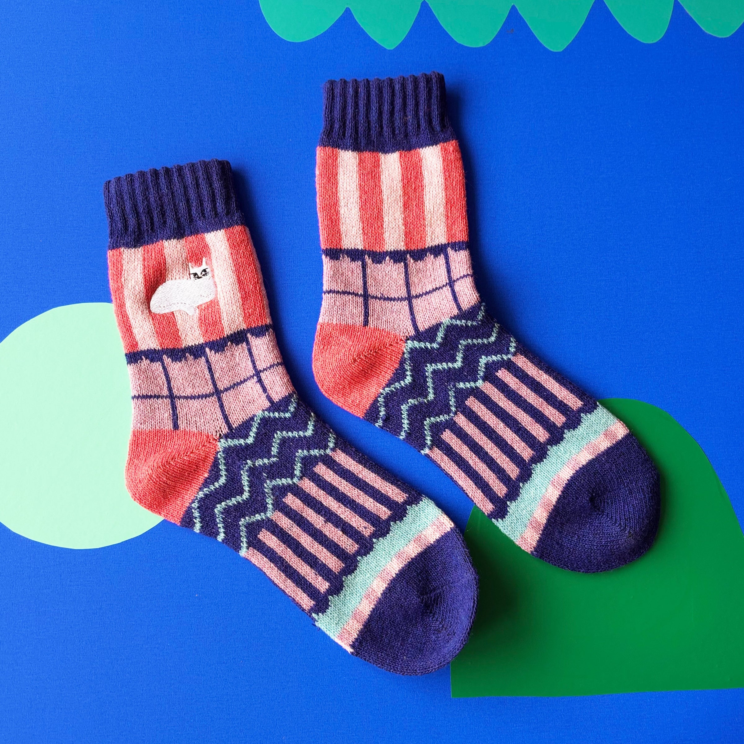 Colourful Catnip Fair Isle Socks featuring stripes, zigzags, and embroidered white cat on bright blue background.