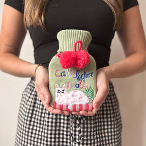 Woman holding Catnip Cats Before Twats hot water bottle with embroidered white cat and slogan.