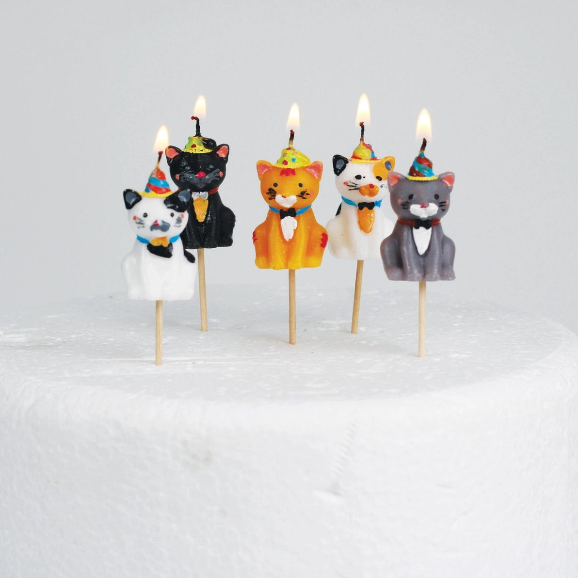 Lit Cats in Party Hats Cake Candles on a cake, showcasing a fun and playful design for a unique cake decoration.