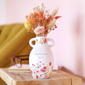 Ceramic Wonderful Mum Floral Vase with dried flowers on a wooden table against a pink backdrop.