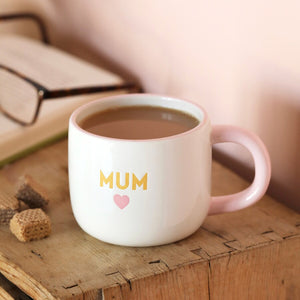 Mum mug filled with tea on a wooden surface with a book in the background.