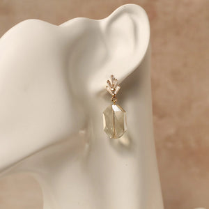 Champagne yellow art deco earrings with crystal fan posts shown worn on an ivory mannequin, highlighting length and elegant drop design.