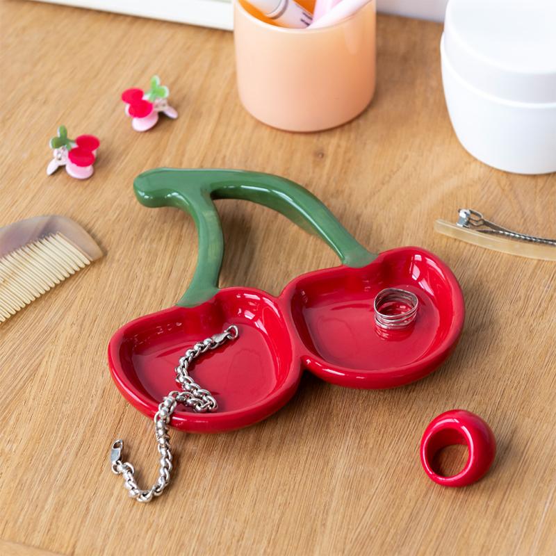 Cherry ceramic dish close-up with jewellery on wooden surface