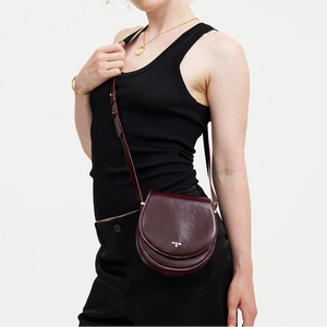 Model wearing Fable England Cherry Red Saddle Bag crossbody style with adjustable strap and gold bee detail.