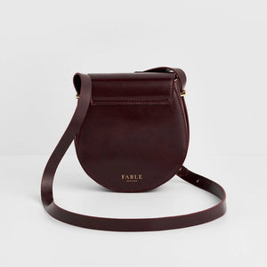 Back view of Fable England Cherry Red Saddle Bag featuring embossed gold Fable logo and sleek saddle shape.