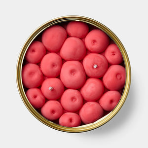 Top-down view of cherry-scented candle with individual cherry-shaped wax pieces packed tightly inside gold tin.