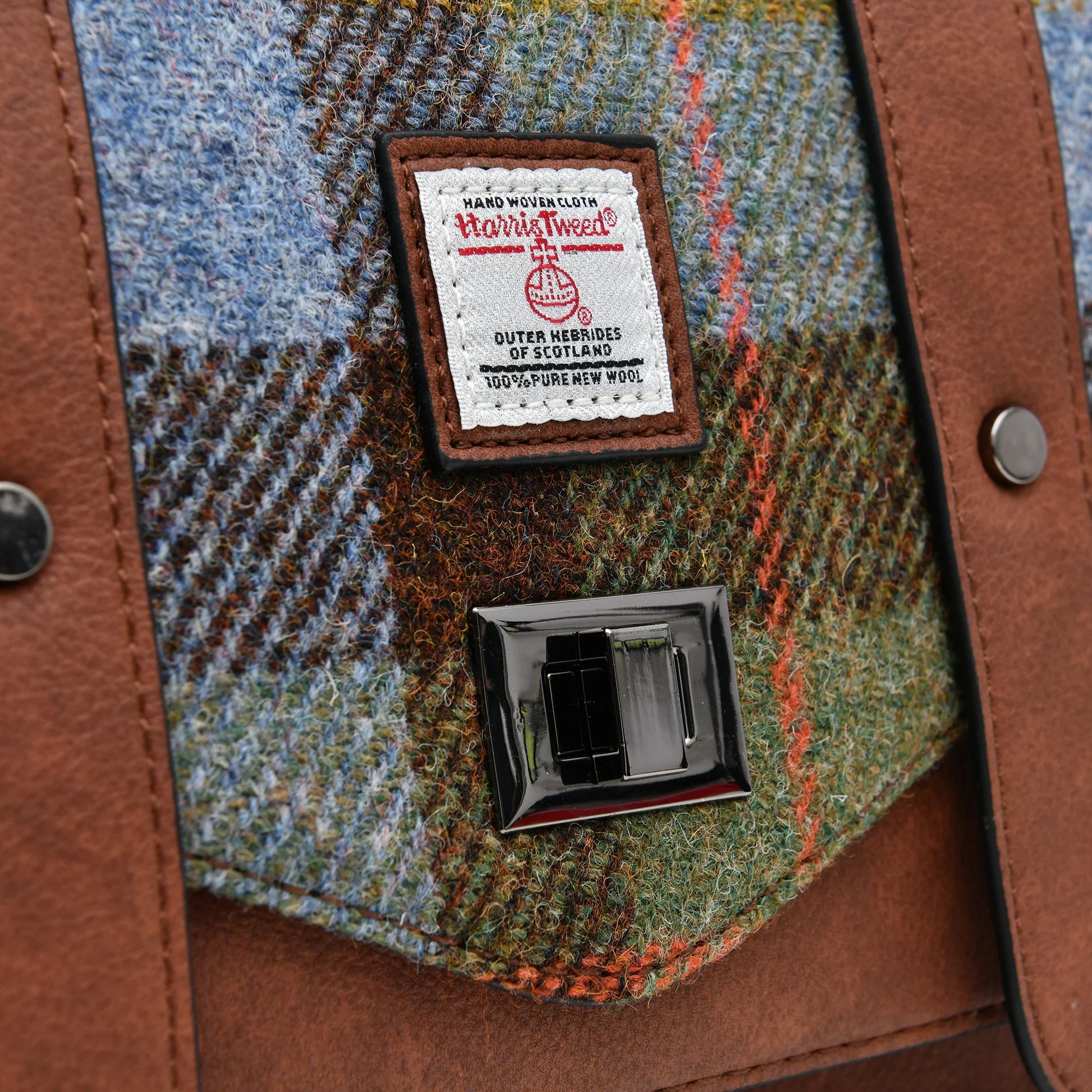 Detailed side view of the satchel highlighting the quality stitching and wool texture of the Harris Tweed fabric.