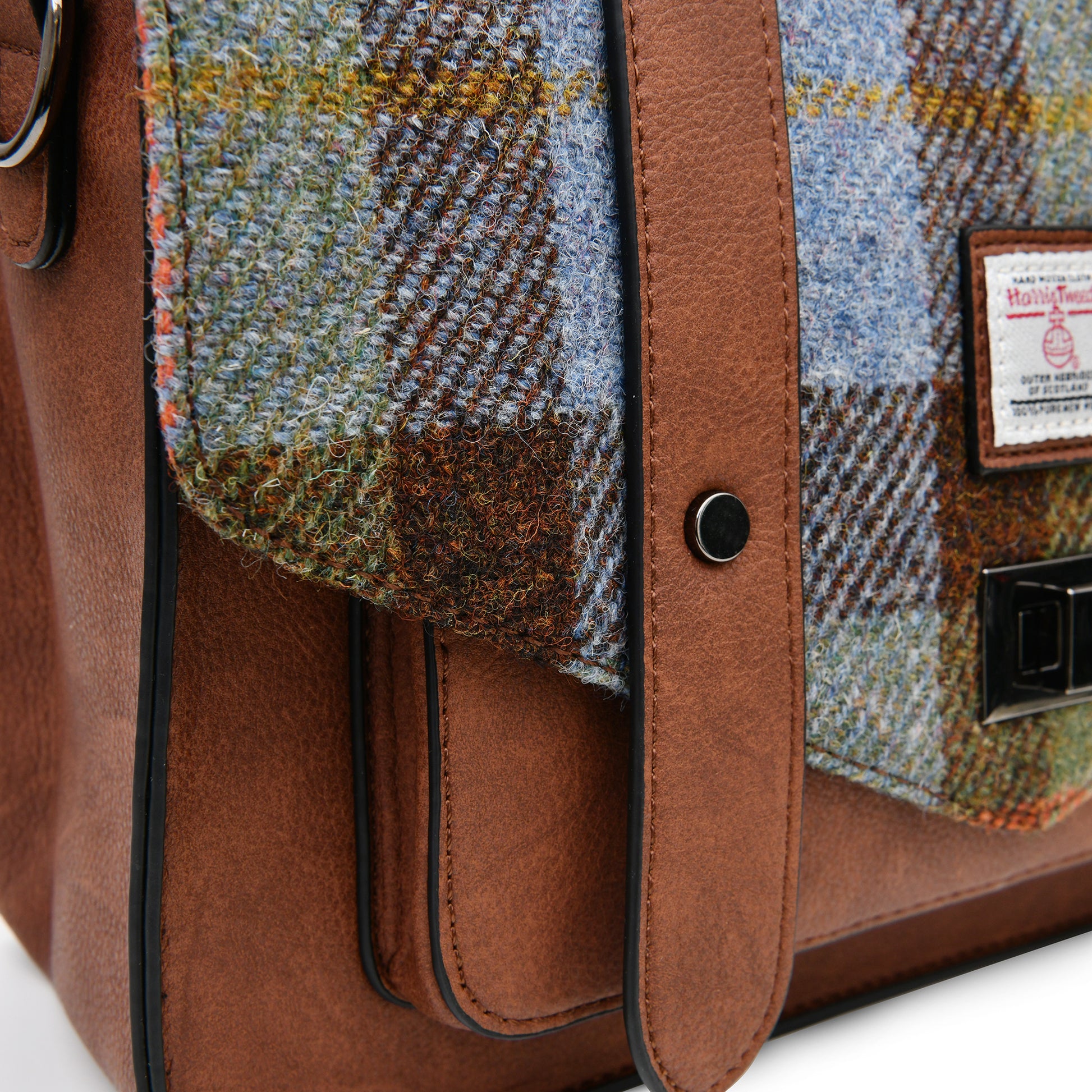 Close-up of the Harris Tweed authentication label and clasp on the Islander Chestnut & Blue Tartan Satchel.