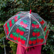 Cherry print transparent dome umbrella held open outdoors by child