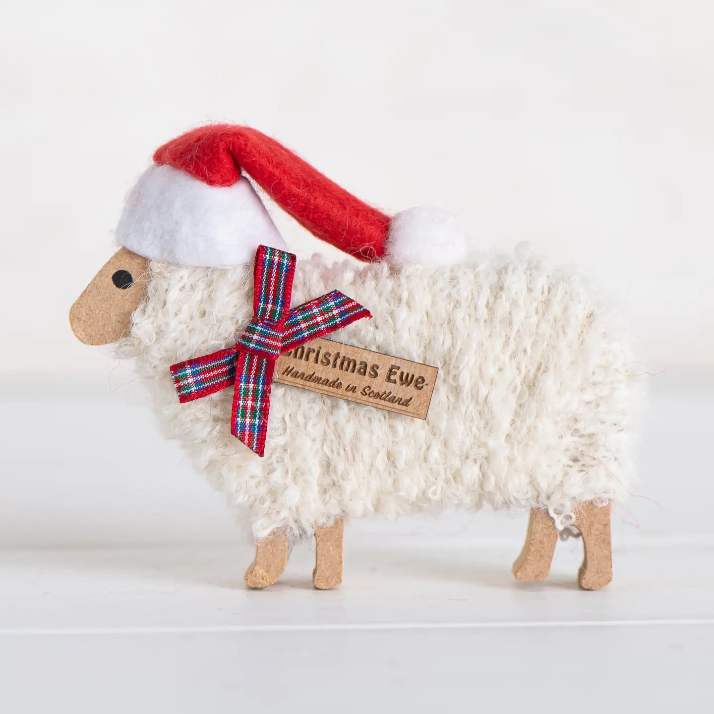 Handmade Christmas Ewe Standing Ornament with Santa hat and tartan ribbon bow, festive Scottish sheep decoration, 8 × 12 × 1.5 cm.