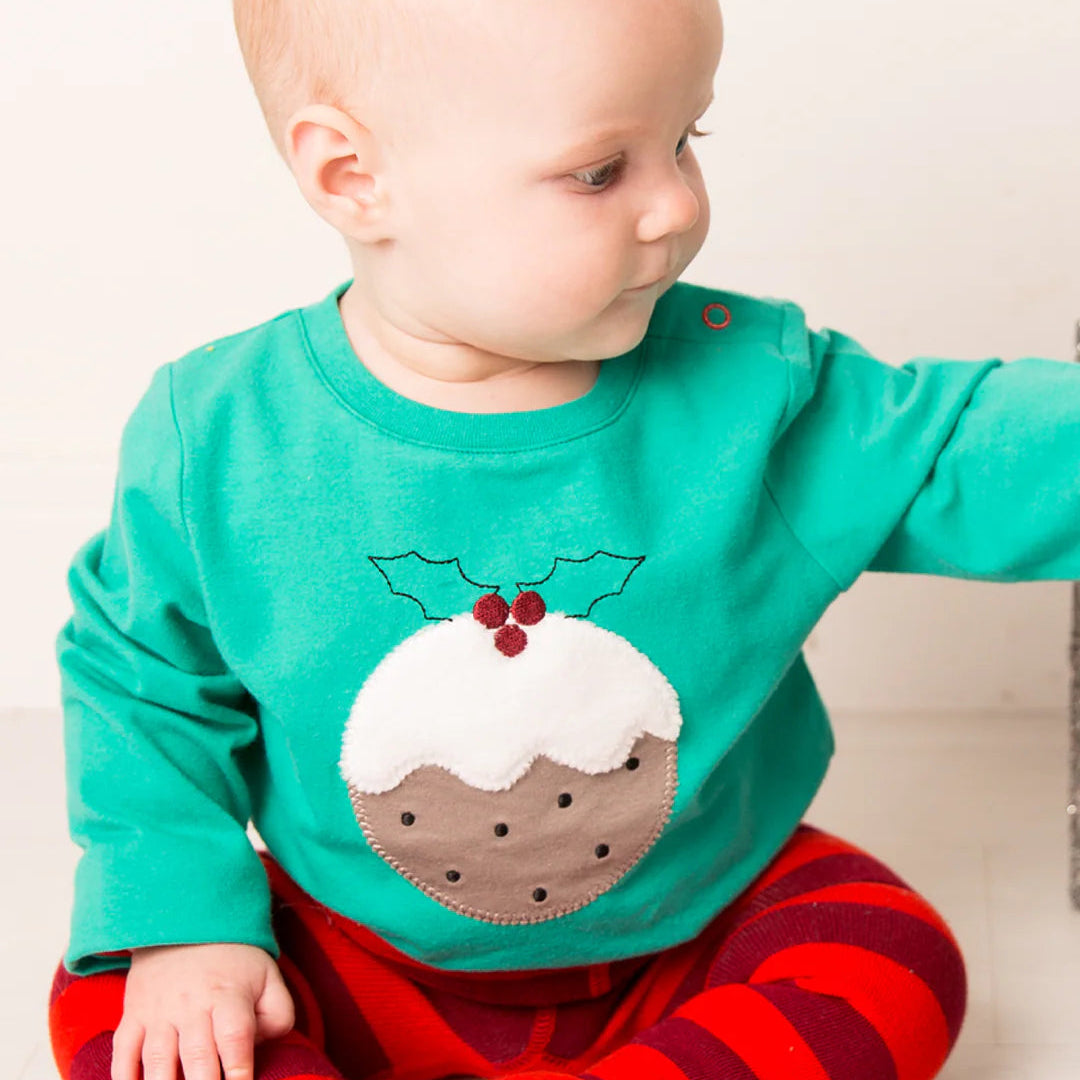 Baby wearing green Christmas Pudding Top with red and green striped leggings, featuring pudding applique and holly design.