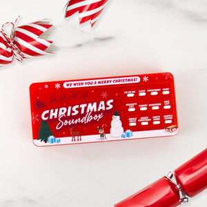 Top-down view of the Christmas Soundbox on a white surface with candy-striped crackers, highlighting its compact size and fun Christmas-themed illustrations.