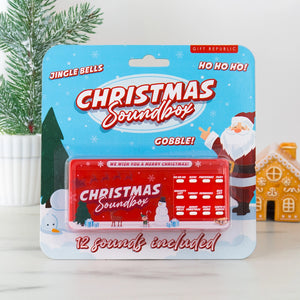 Front view of the Christmas Soundbox in festive retail packaging, featuring Santa, snowflakes, and 12 labelled sound buttons including “Ho Ho Ho” and “Jingle Bells”.