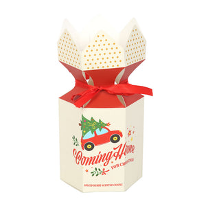 Gift box for Coming Home For Christmas candle tied with red ribbon and festive print.