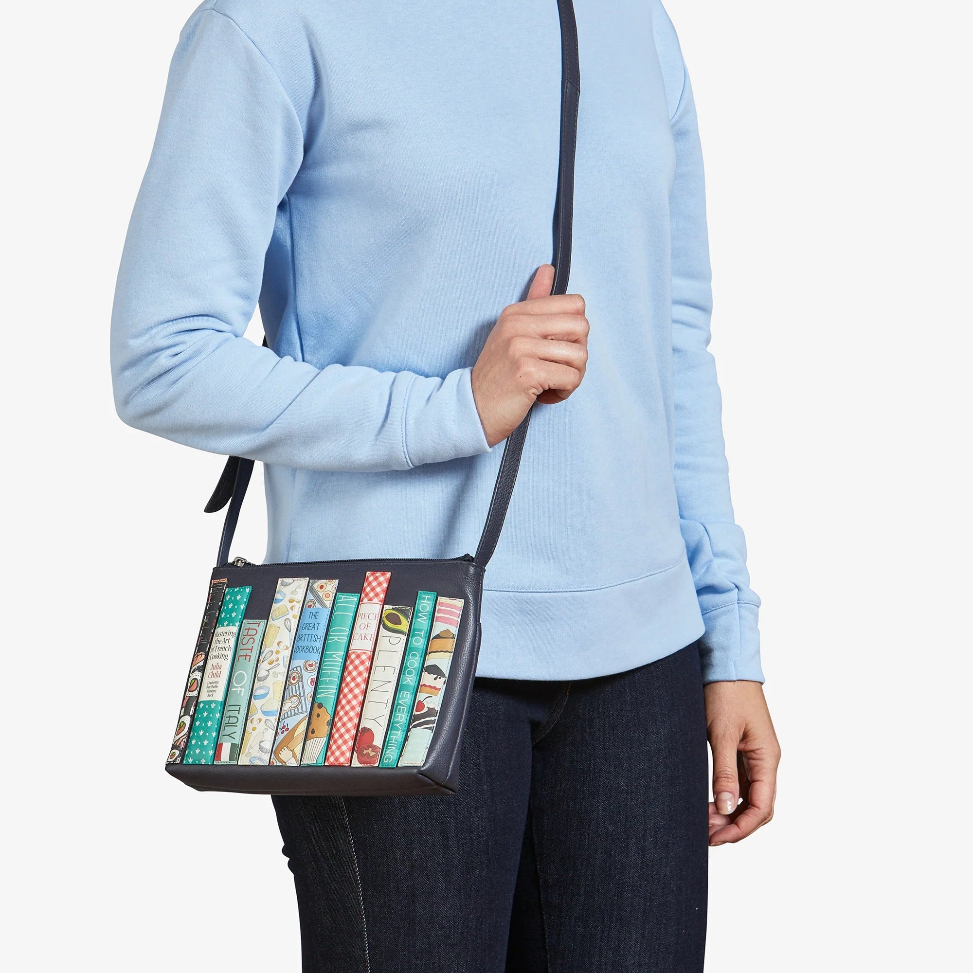 Model wearing Cook Bookworm Parker Leather Cross Body Bag crossbody style with cookbook appliqué front.