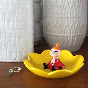 Disaster Designs Moomin Little My ring dish placed on a wooden surface, with a white ceramic vase in the background.