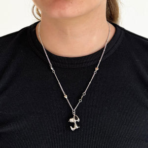 A close-up of a person wearing the silver Snoopy necklace, featuring a delicate chain with small heart details.