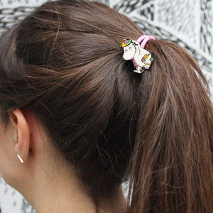 A woman wearing the Snorkmaiden Enamel Hairband in a high ponytail, featuring a pink elastic band and an enamel Snorkmaiden charm.