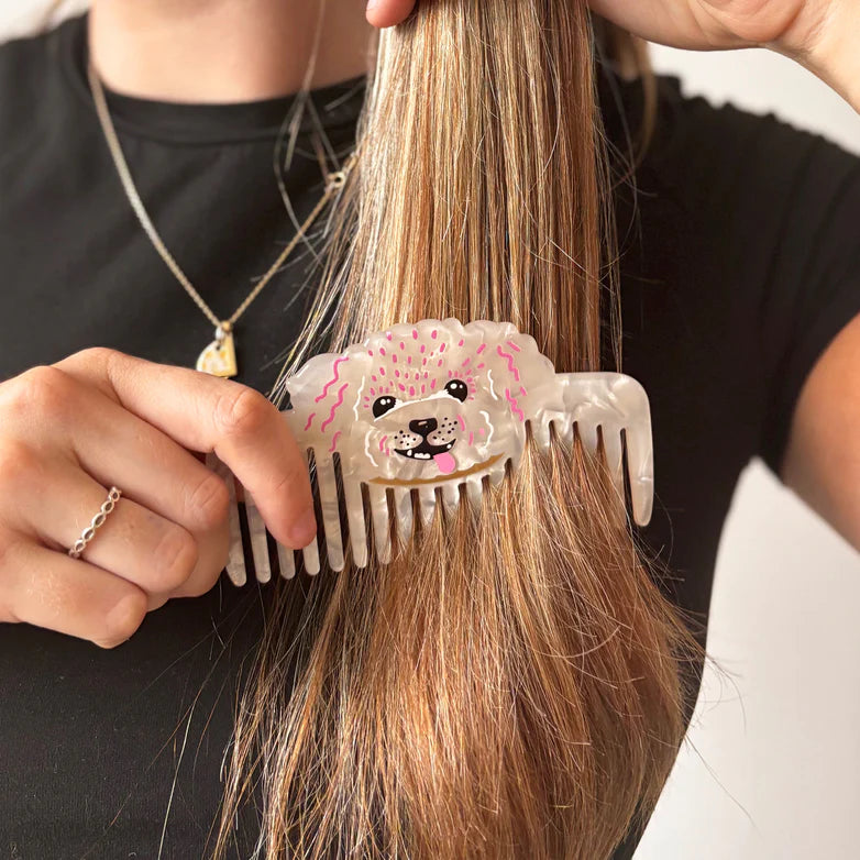 Woman combing hair with dog-shaped pearlescent comb – Dog House Hair of the Dog Comb in use.