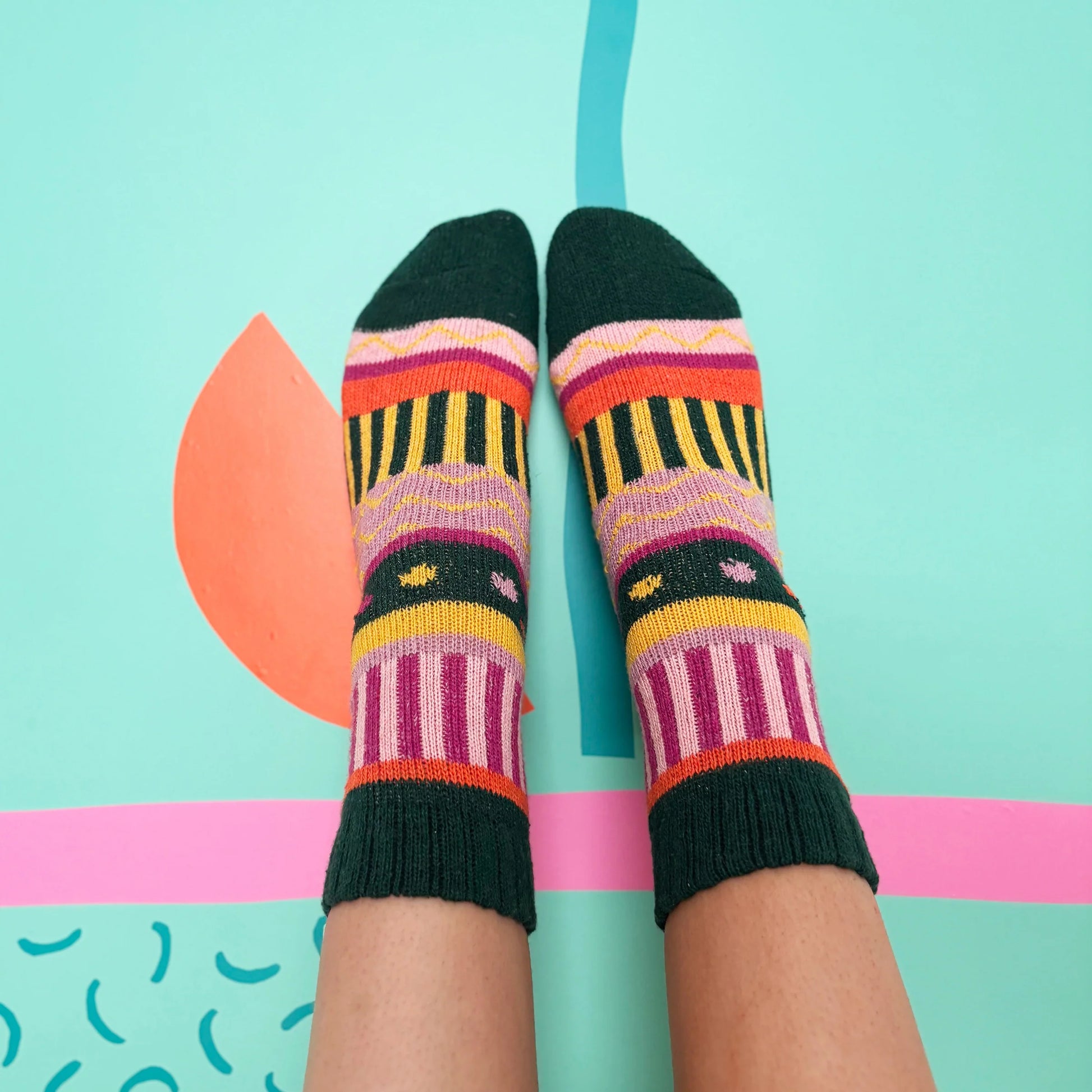 Overhead view of feet wearing Doghouse Fair Isle Socks on teal floor.