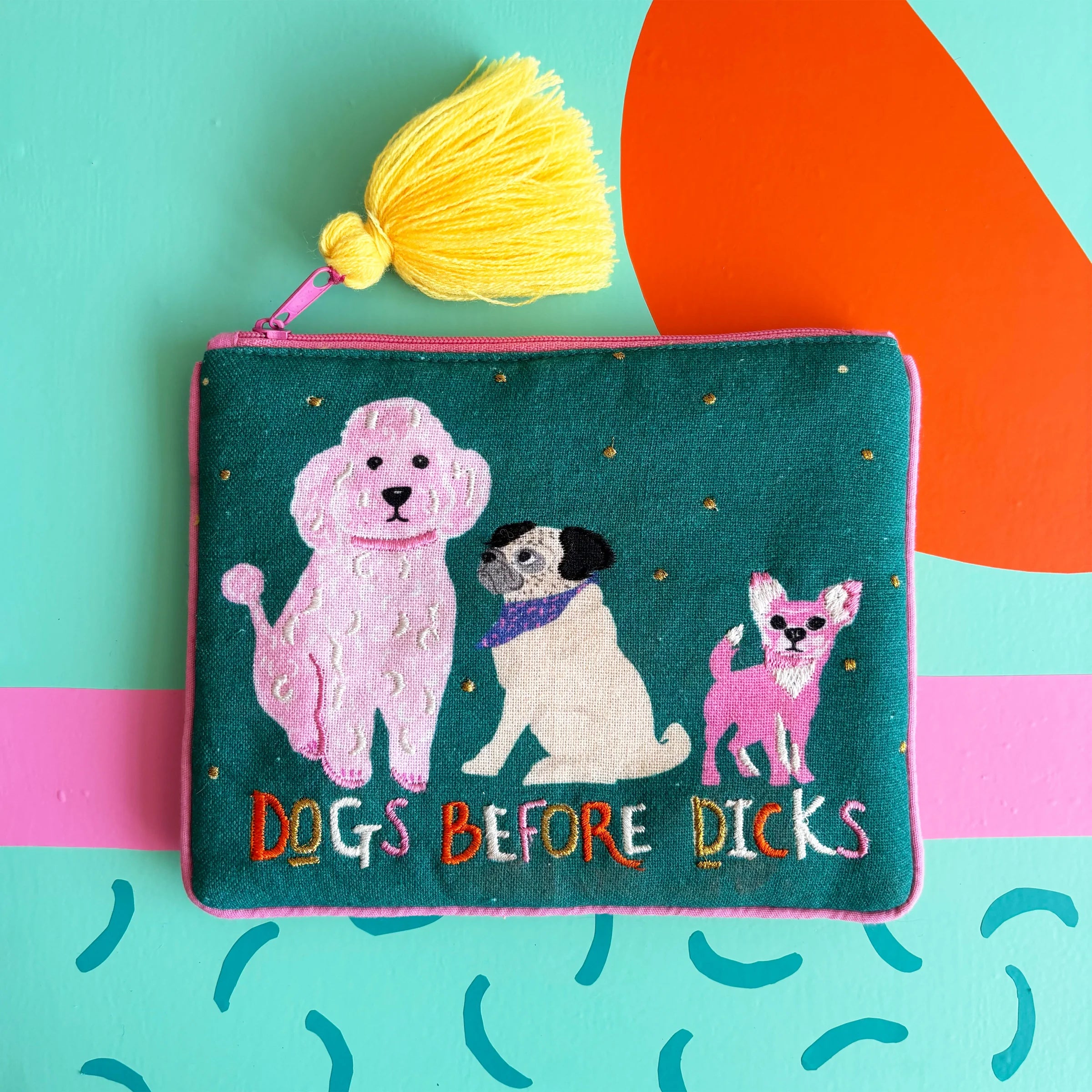 Flat lay of green pouch with colourful slogan and dog embroidery.