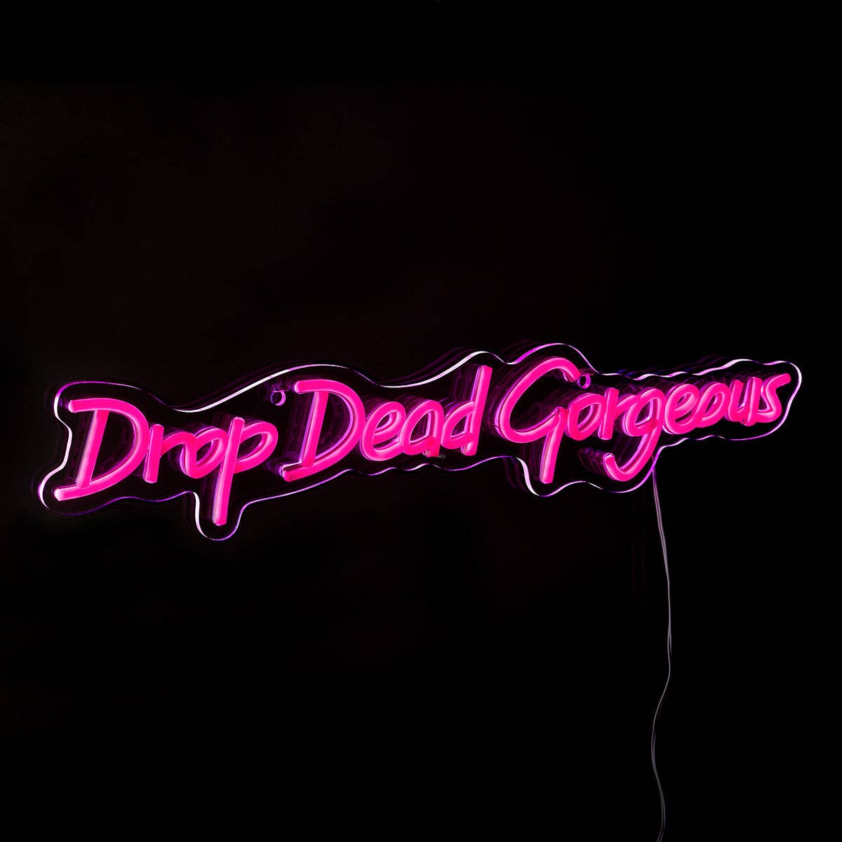 Illuminated pink Drop Dead Gorgeous neon sign glowing in a dark room.