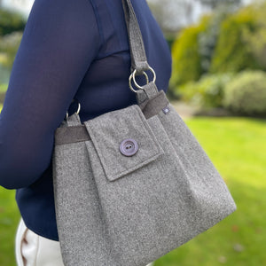 Woman's shoulder with a Grey Earth Squared Juniper Anna Bag, highlighting its compact size and practical features.