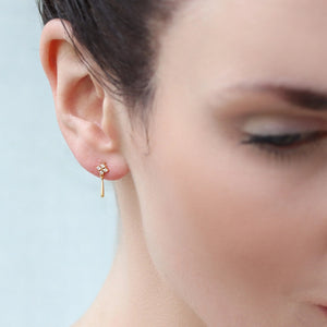 Model wearing Edwardian-inspired gold drop stud earrings with tiny zirconia stones, showing how they sit just below the earlobe.