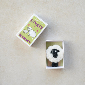 Flat lay of an open matchbox with a wool felt sheep and tiny envelope inside.