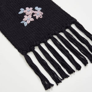 Close-up of Fable Forget-Me-Not Knitted Navy Scarf showing detailed pink and blue floral embroidery with tassel edging.