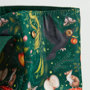 Side Button Detail: A detailed shot of the side snap button closure, featuring woodland artwork of a crow, apples, and mushrooms.