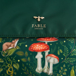 Front Flap Close-up: A zoomed-in image of the Fable England bee emblem on the green flap, with the intricate woodland print, including mushrooms and a vole, in the background.