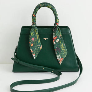 Front View – A structured green tote bag with a whimsical woodland print scarf wrapped around the handle, featuring gold bee detailing.