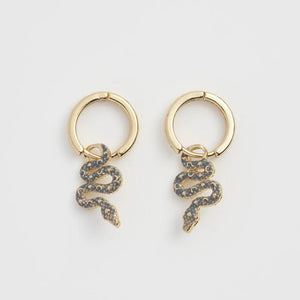 Close-up of Fable England Celestial Snake Huggie Earrings featuring gold-plated snake charms with celestial enamel detailing.