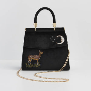 Front View: A luxurious black velvet tote bag featuring intricate embroidery of a fawn standing beneath a crescent moon with delicate star details. The bag has a structured shape, a gold-tone top handle, and a detachable gold chain strap.