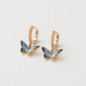 Close-up of Fable England Enamel Blue Butterfly Huggie Earrings displayed on a white background.