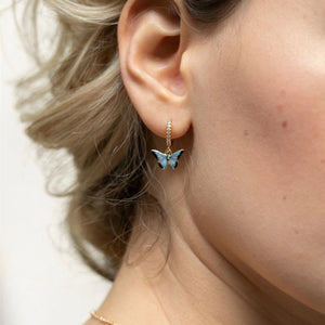 Woman wearing the blue butterfly huggie earrings, showcasing their delicate and elegant design.