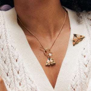 Model wearing the Moth & Leaf Charm Necklace, styled with a matching enamel moth brooch.