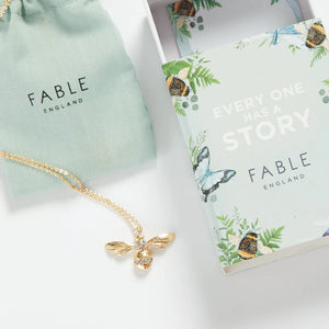 Fable England Enamel Short Bee Necklace in gift packaging – The bee necklace displayed with a branded cotton pouch and a beautifully illustrated gift box.