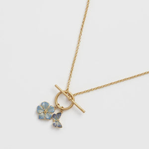 Close-up of the Fable England Forget Me Not Charm Toggle Necklace featuring a gold-plated chain with butterfly and flower charms.