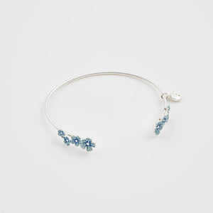 Front view of Fable Forget-Me-Not Silver Bangle with blue enamel flowers and signature charm on a white background.